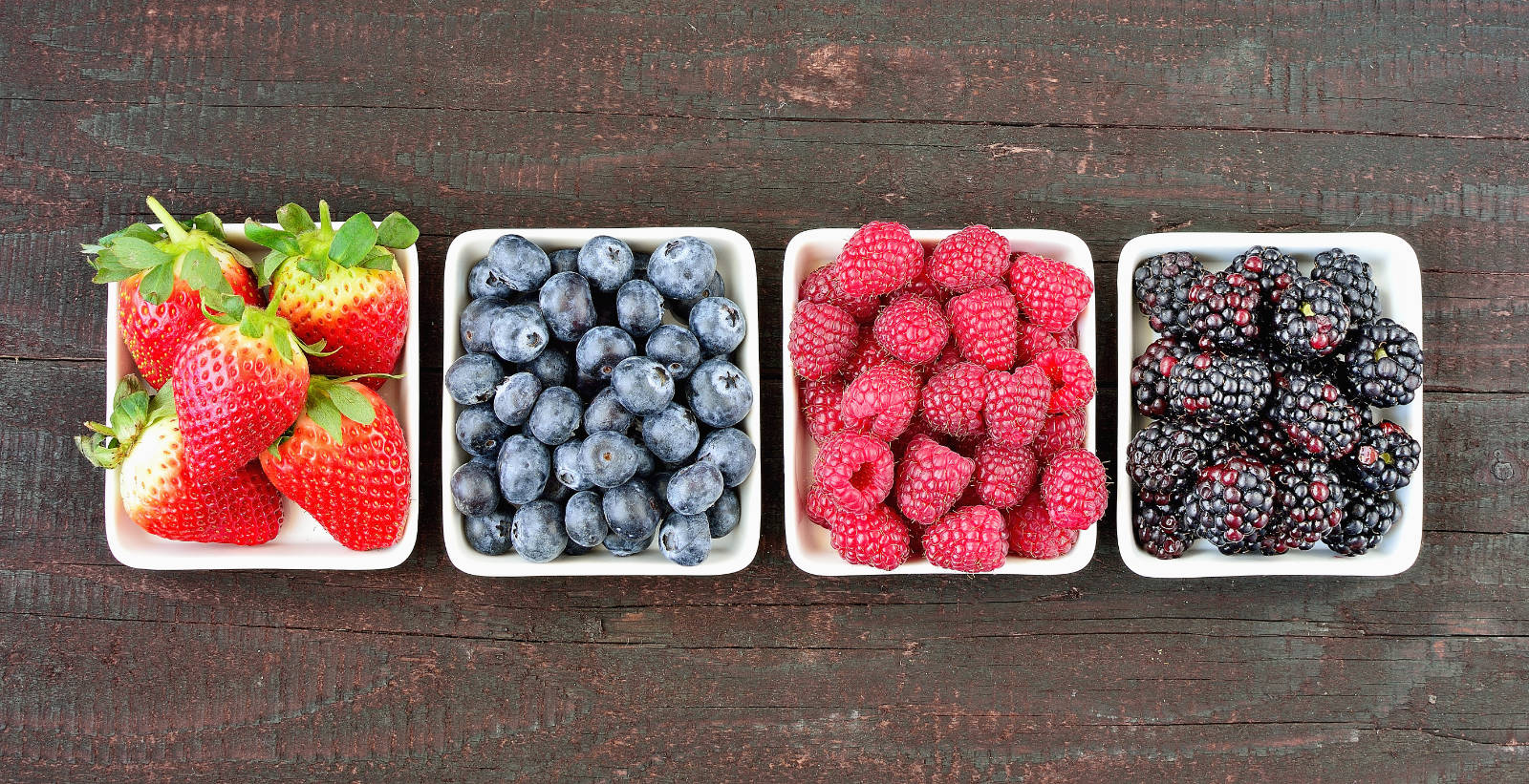 Mix,of,strawberries,,blueberries,,blackberries,and,raspberries,fruit,on,wood
